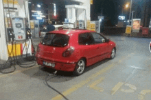 a red car is parked in a gas station with the number 69 on the pump