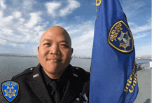 a man in an oakland police uniform holds a flag