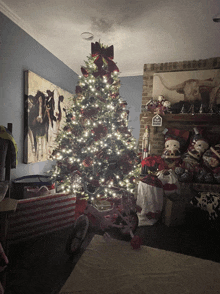 a christmas tree in a living room with a painting of cows on the wall behind it