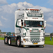 a white and green scania super truck is parked in a parking lot