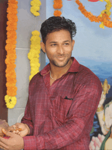 a man in a plaid shirt is smiling in front of a wall with flowers