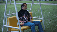 a man is sitting on a swing wearing a sweater that says ' samurai ' on it