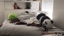 a stuffed panda bear is laying on a bed .