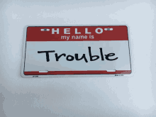 a red and white hello my name is trouble name tag