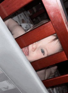 a baby laying in a wooden crib with a pacifier in her mouth