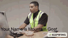 a man in a security vest sits at a desk in front of a computer with the words " your name is mountain goat " below him