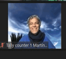 a man in a blue shirt is smiling in a video call with tally counter 1 martin .