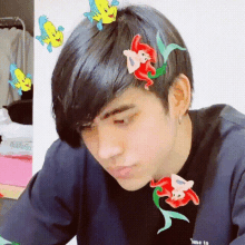 a young man with fish and flowers in his hair is wearing a black shirt .