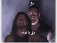 a couple of men standing next to each other in a dark room with arabic writing on it .