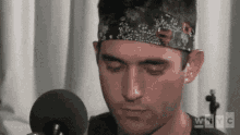 a man wearing a headband is sitting in front of a microphone