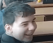 a young boy is smiling while sitting at a table .