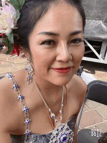 a woman with a flower in her hair is wearing a necklace that says b612 on the bottom