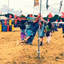 a man is hanging upside down on a pole in a field with a sign that says ' recycling ' on it