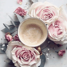 a cup of coffee surrounded by pink and white roses