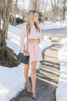 a woman wearing a pink dress and a black chanel purse