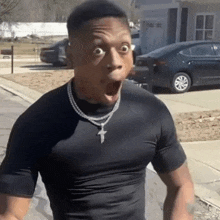 a man wearing a black shirt and a cross necklace is making a funny face .