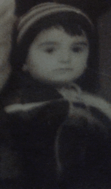 a black and white photo of a child with a striped hat on