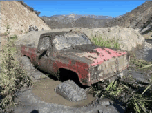 a red truck is stuck in a muddy area and has the word monster painted on the side