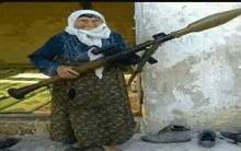 an elderly woman is holding a rifle and a rocket launcher in her hands