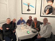 a group of men are sitting around a table with glasses of wine