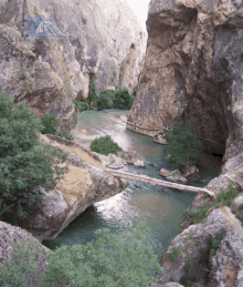 a bridge over a river surrounded by rocks and trees with a sign in the background that says " turkey "