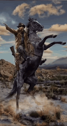 a man in a cowboy hat is riding a horse in the desert