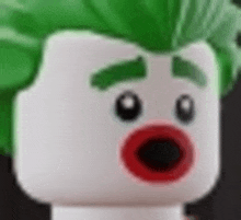 a close up of a lego joker head with green hair and red lips .