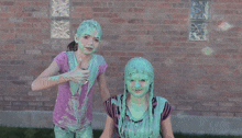 two girls with green slime on their faces are standing in front of a brick wall