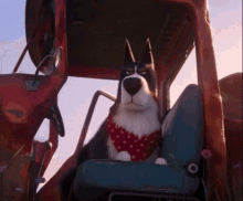 a dog wearing a red and white polka dot bandana is sitting in the driver 's seat of a vehicle