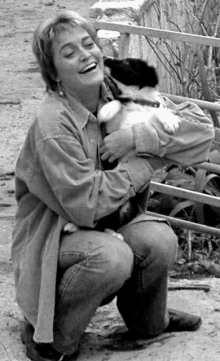 a woman is kneeling down holding a puppy in her lap