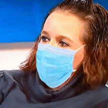 a woman wearing a blue face mask is looking at the camera