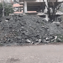 a large pile of rocks is sitting on the side of a road in front of a building under construction .