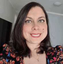 a woman in a floral dress is smiling for the camera .