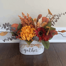 a white bucket filled with flowers and leaves is sitting on a wooden floor .