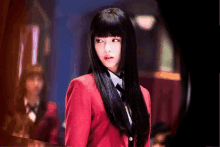 a woman with long black hair and a red jacket and tie