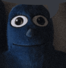 a close up of a blue cartoon character with big eyes and a smiling face .