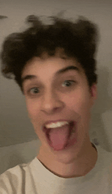 a young man is sticking his tongue out while taking a selfie .