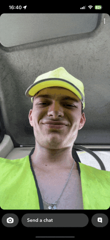 a phone screen shows a man wearing a yellow hat and a green vest