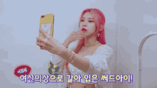 a woman with pink hair is taking a picture of herself with a cell phone