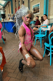 a woman in a pink bodysuit is dancing on a patio