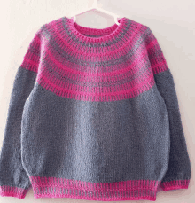 a grey and pink sweater is hanging on a hanger