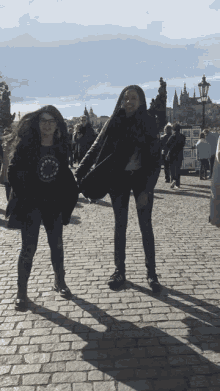 two women walking down a cobblestone street with one wearing a shirt that says ' i love you ' on it