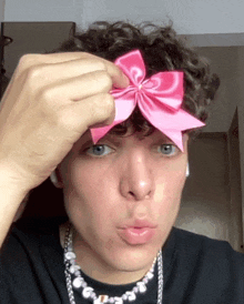 a man wearing a black shirt and a pink bow on his head