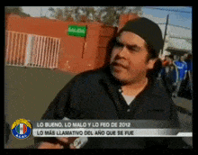 a man wearing a black hat is talking to a camera in front of a sign that says " salida "