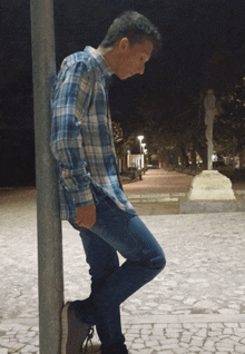 a man leaning against a pole in a park