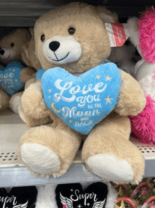 a teddy bear is holding a blue heart that says love you to the moon and back