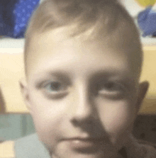 a close up of a young boy 's face with a gray shirt on .