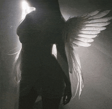 a woman with angel wings is standing in a dark room .