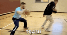 two men are playing basketball on a court and one of them is holding a basketball in his hand .