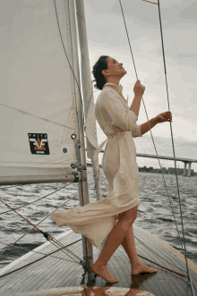 a woman in a white dress stands on a sailboat with a fritz vf sticker on the sail